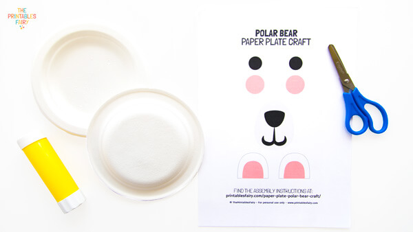 From left to right: glue stick, 2 white paper plates, polar bear template, and scissors