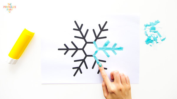 Gluing cyan paper scraps on the snowflake outline