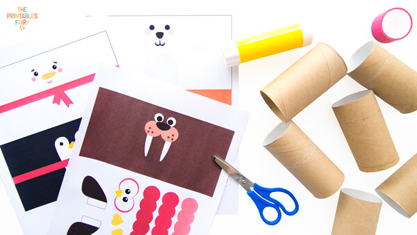 From left to right: winter characters templates, glue stick, scissors, 6 toilet paper rolls, and tape.