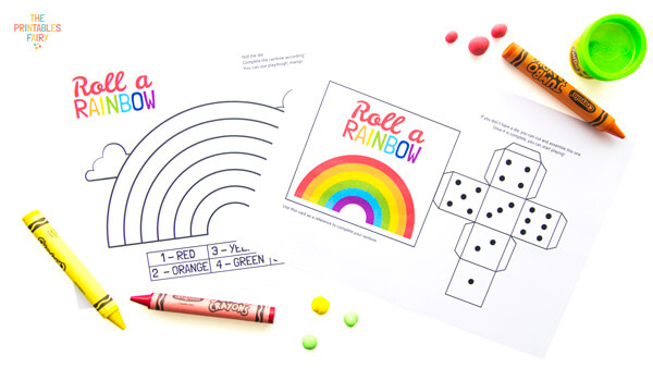 Roll a rainbow game, crayons, and playdough on a white table